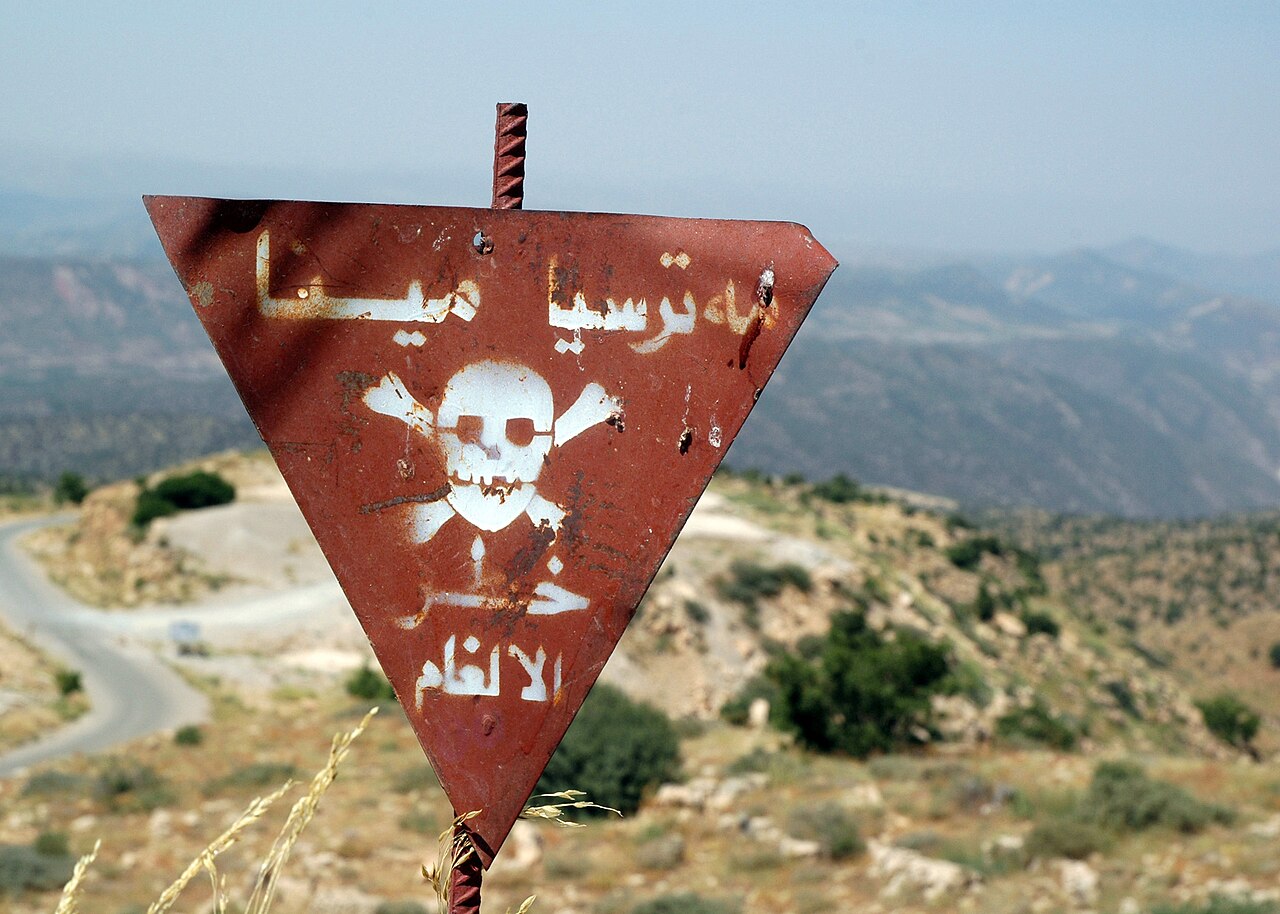 Researcher Warns AI Infrastructure Financing Poses Systemic Risks — This sign warns about a minefield planted in the rough hilly terrain behind it, in an area near Arbil, Arbil Province, Iraq (IRQ)